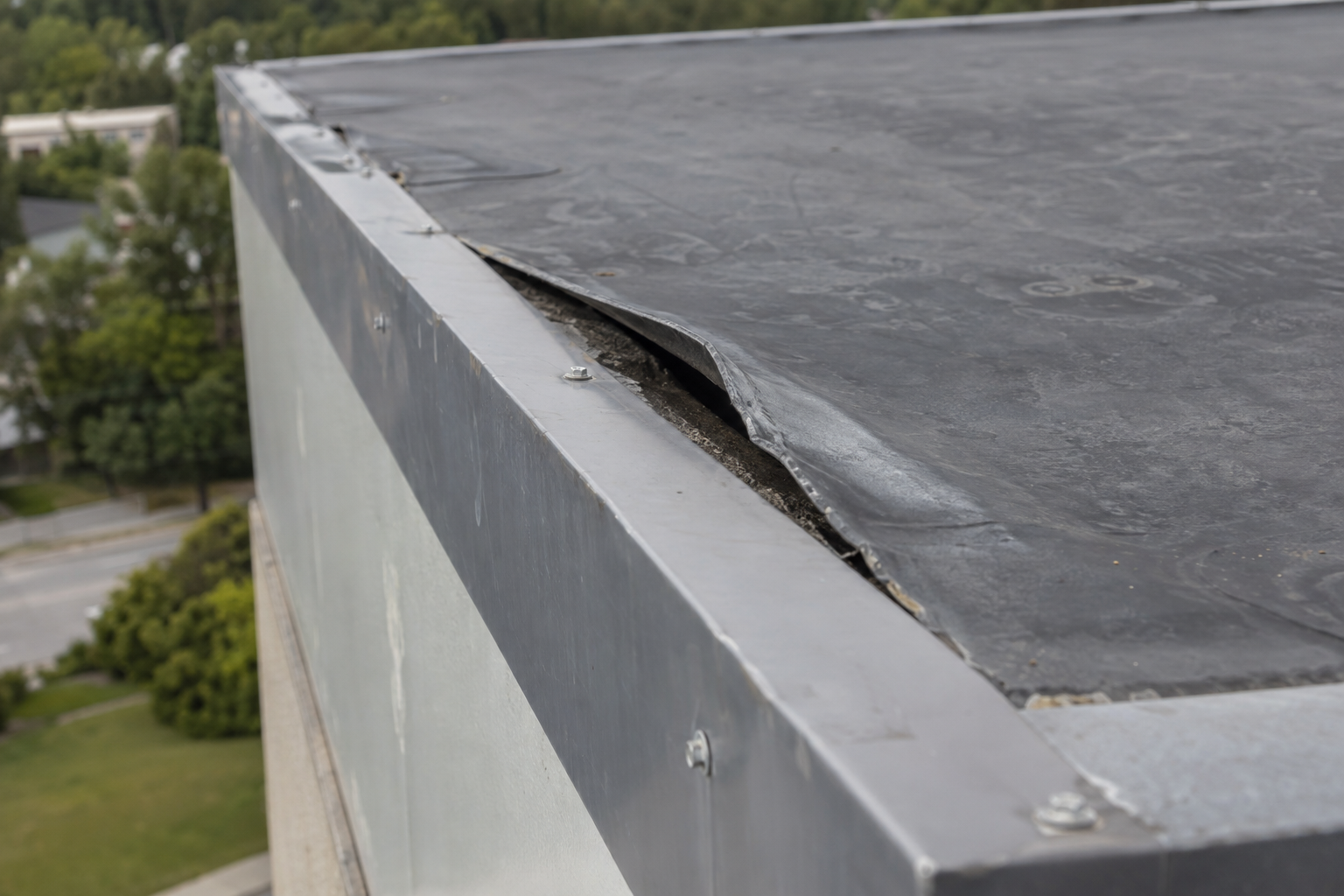 Corner of a low-slope roof where the membrane has pulled away from the metal edge